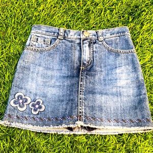 A size five jean skirt with two flower patches.